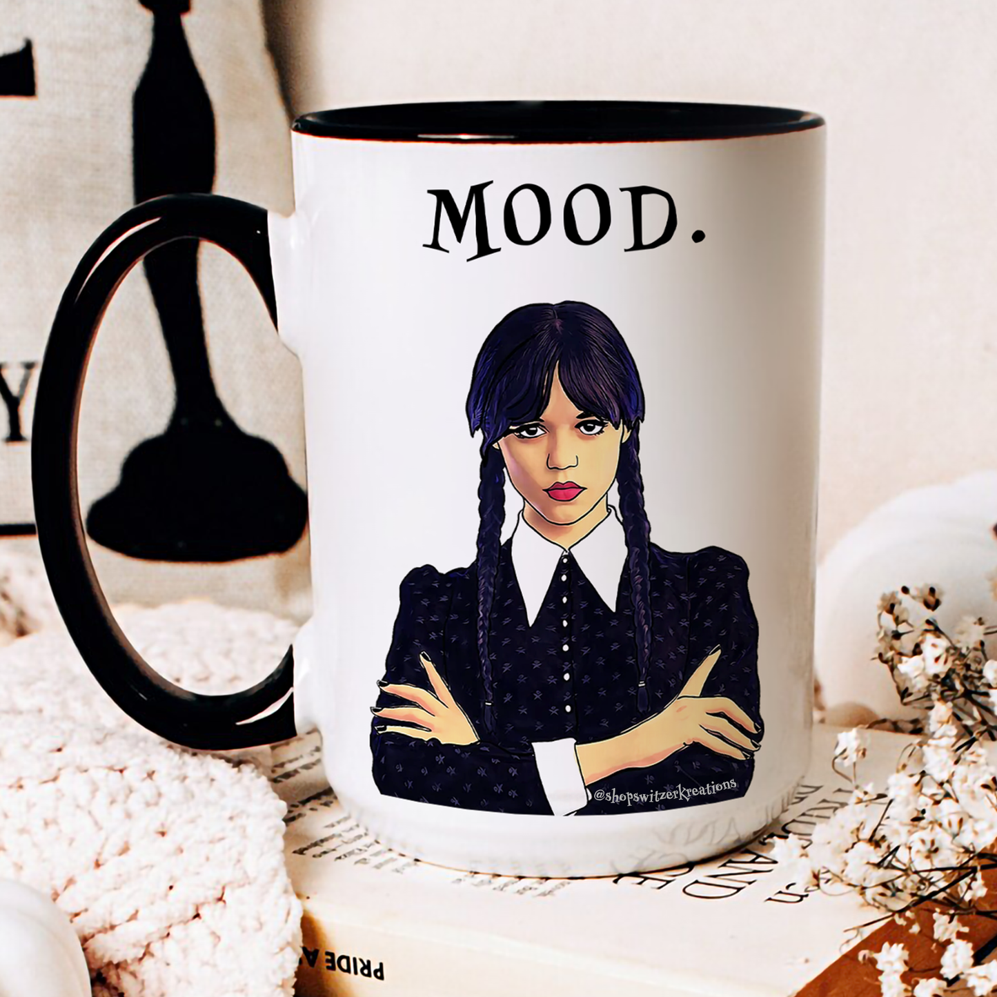 A black and white ceramic coffee mug featuring an illustration of Wednesday Addams with a deadpan expression. Below the image is the word “MOOD” in bold, black text. The design is printed on both sides, making it suitable for right- or left-handed users. A perfect gift for fans of dark humor and gothic style.