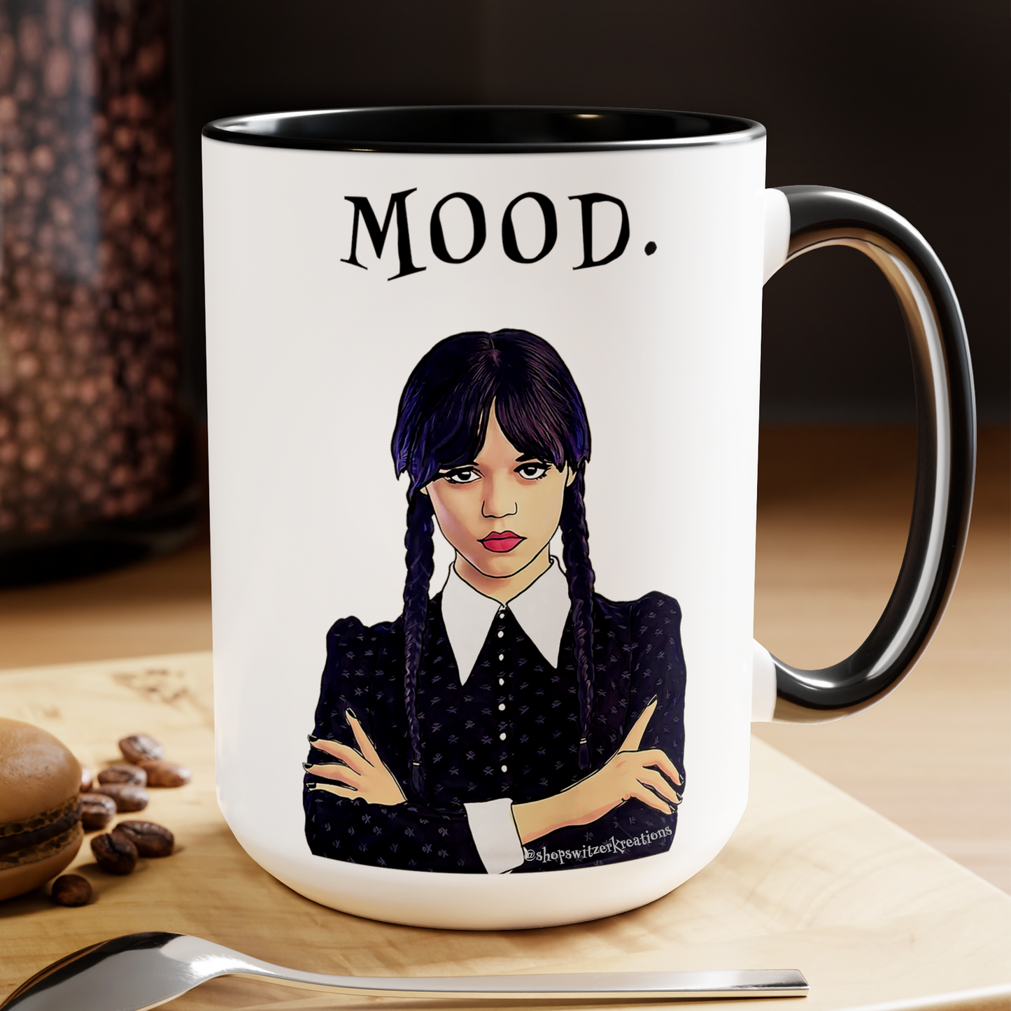 A black and white ceramic coffee mug featuring an illustration of Wednesday Addams with a deadpan expression. Below the image is the word “MOOD” in bold, black text. The design is printed on both sides, making it suitable for right- or left-handed users. A perfect gift for fans of dark humor and gothic style.