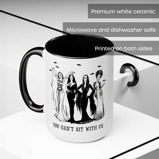 A white ceramic mug with a black interior, black handle, and black printed graphic of four women with the text 'YOU CAN'T SIT WITH US.' The image includes text overlays stating 'Premium white ceramic,' 'Microwave and dishwasher safe,' and 'Printed on both sides.
