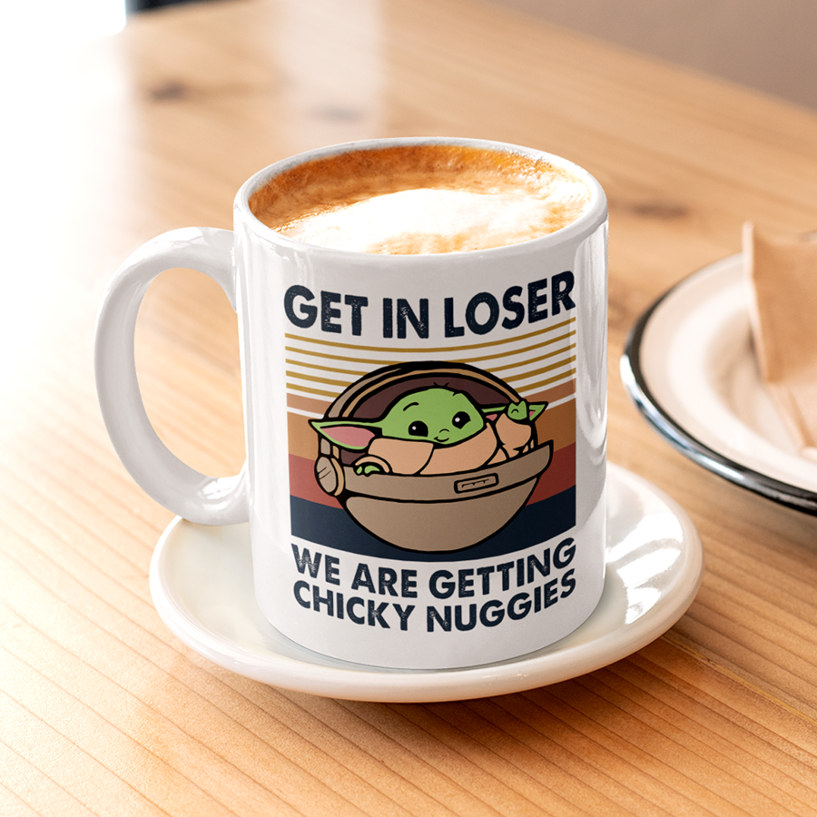 A white ceramic coffee mug featuring an illustration of Grogu in a hover pram with the funny phrase "Get In Loser, We Are Getting Chicky Nuggies." The design is printed on both sides, making it perfect for right- or left-handed users. A cute and humorous gift for sci-fi fans, coffee lovers, and pop culture enthusiasts.