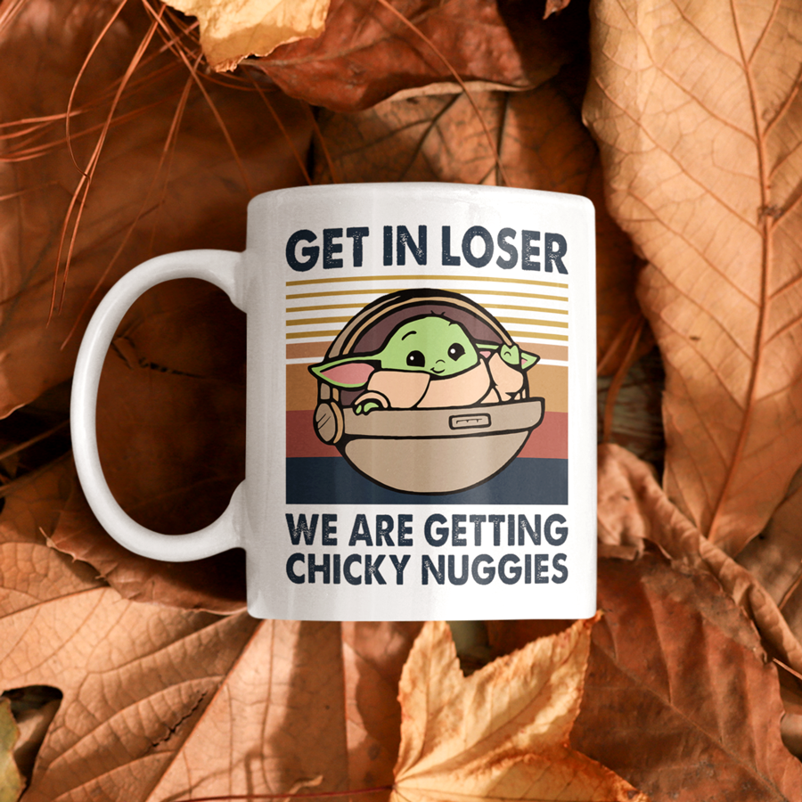 A white ceramic coffee mug featuring an illustration of Grogu in a hover pram with the funny phrase "Get In Loser, We Are Getting Chicky Nuggies." The design is printed on both sides, making it perfect for right- or left-handed users. A cute and humorous gift for sci-fi fans, coffee lovers, and pop culture enthusiasts.