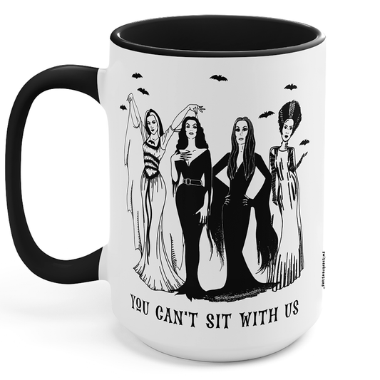 A white ceramic mug with a black handle and black interior, featuring a black line art illustration of four gothic women and the text 'YOU CAN'T SIT WITH US' on the front.